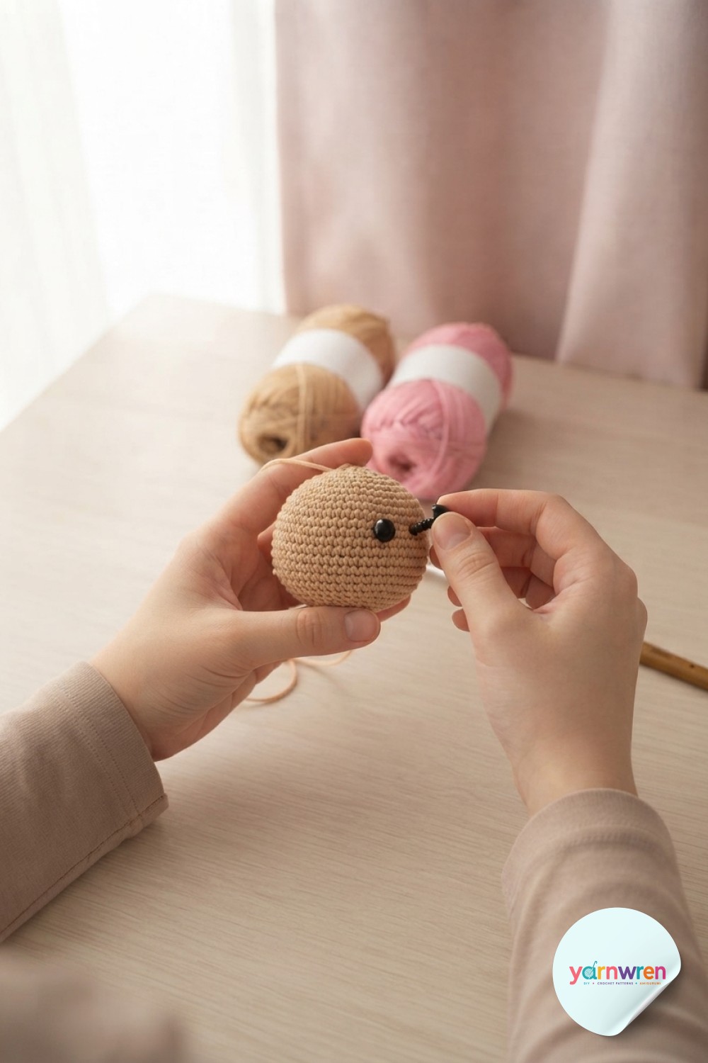 Positioning black safety eyes on the unstuffed head of a crochet puppy amigurumi before closing the round