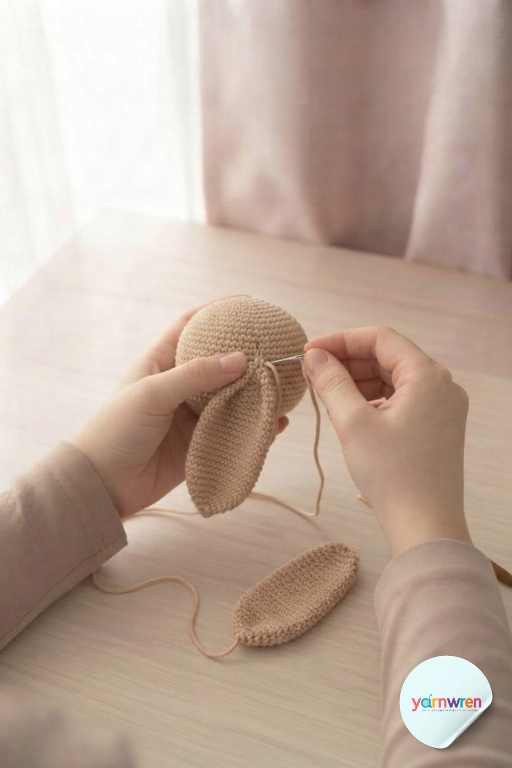 Sewing a floppy ear onto the head with a yarn needle while assembling this crochet puppy amigurumi