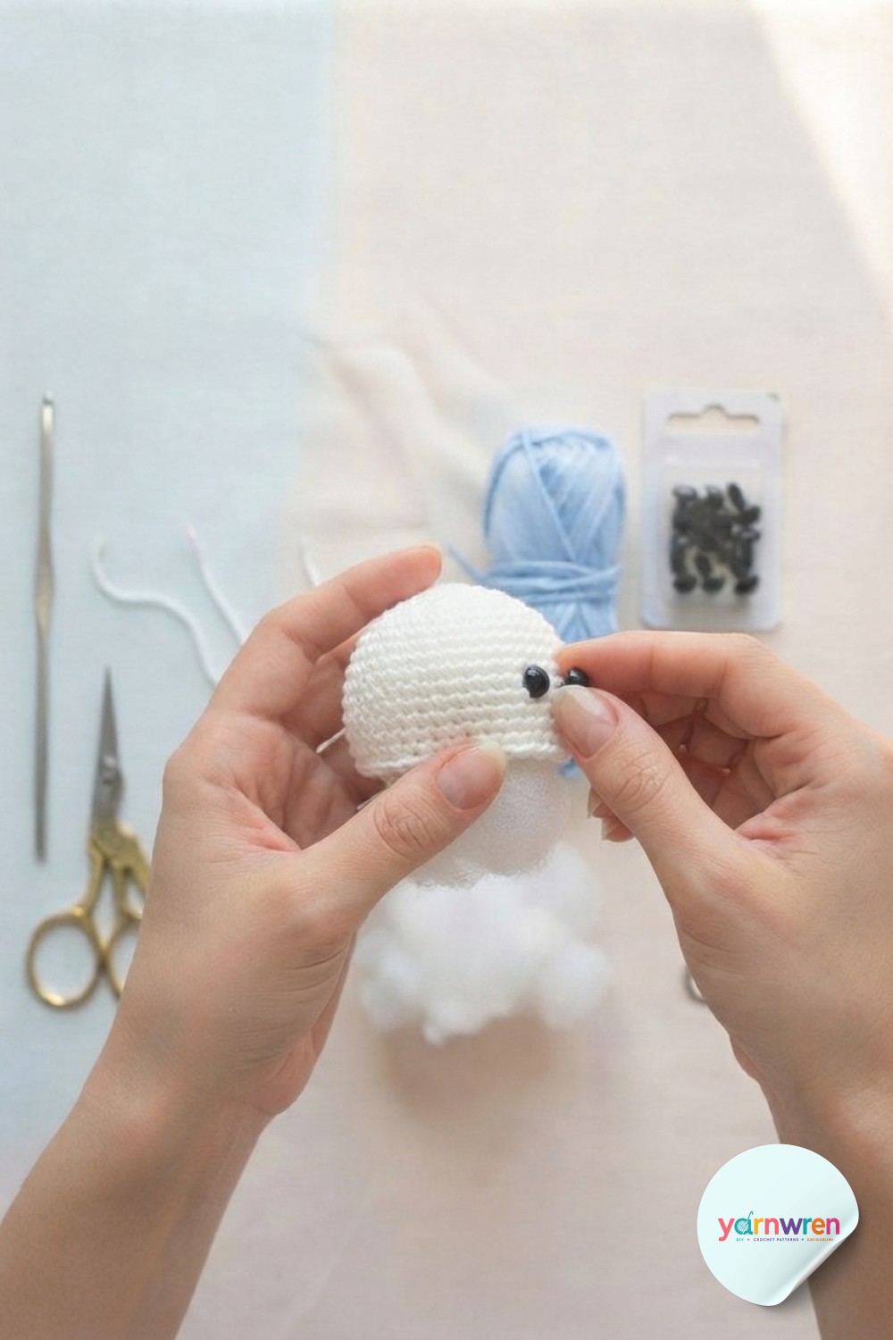 Attaching black safety eyes to a stuffed white dome during jellyfish keychain crochet assembly