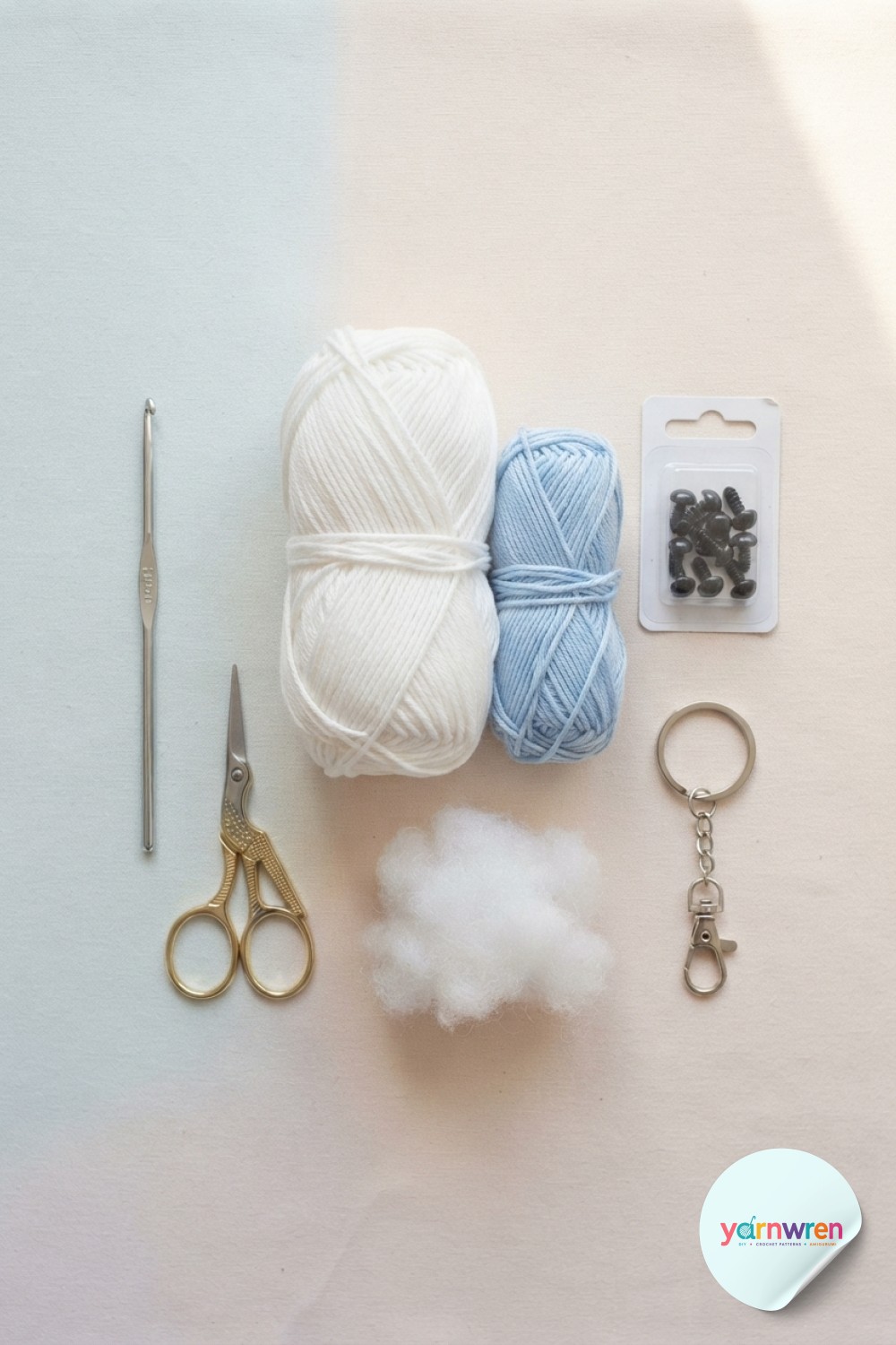 Flat lay of white and blue cotton yarn, hook, and keyring for jellyfish keychain crochet materials